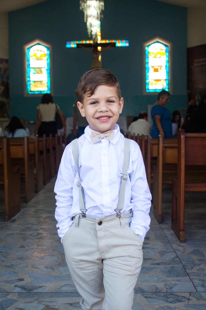 Menino sorridente de suspensórios na igreja
