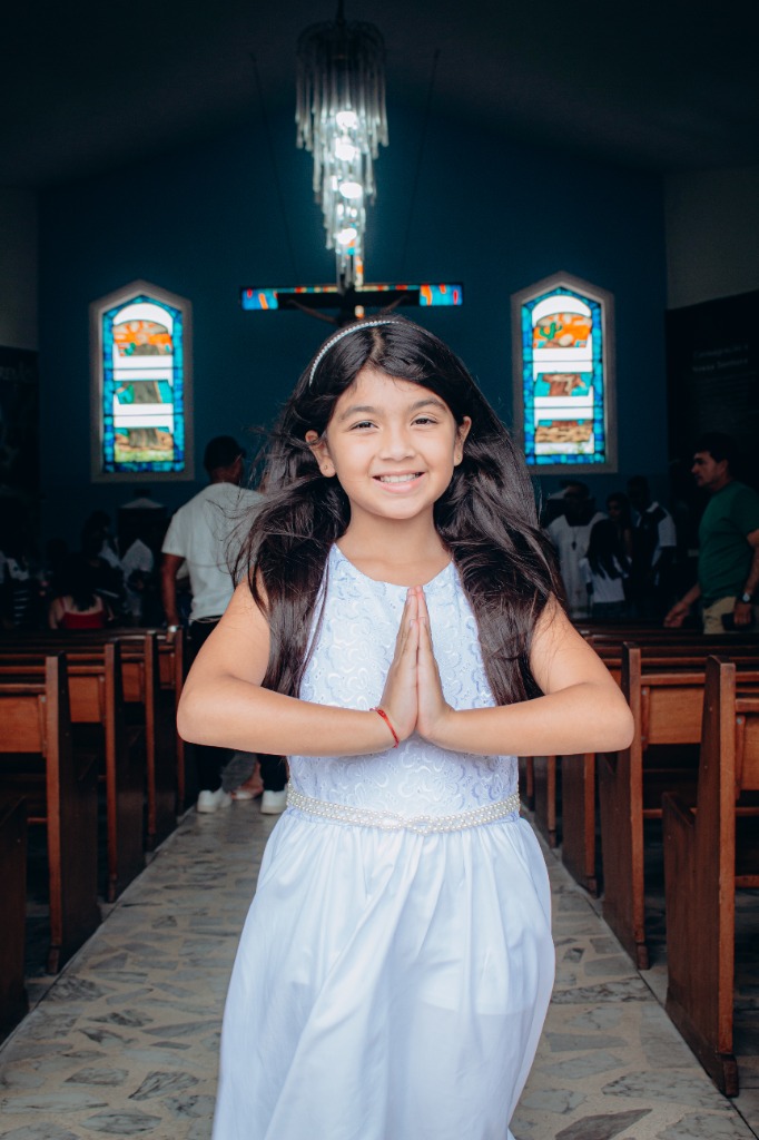 Menina com mãos em prece na igreja