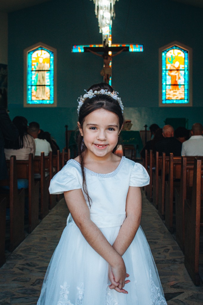 Menina com coroa de flores no corredor da igreja