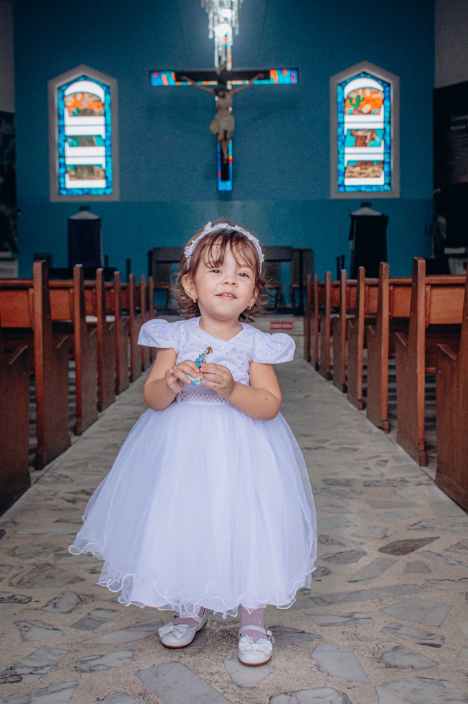 Menina pequena com vestido branco rodado na igreja